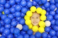 Smiling little girl playing with color plastic balls playground