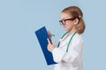 Smiling little girl playing doctor, wearing long white robes with stethoscope Royalty Free Stock Photo