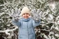 Smiling little girl playing with snow on her gloves. Happy child walking in winter forest Royalty Free Stock Photo