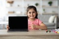 Smiling Little Girl Pointing At Laptop With Blank Black Screen At Home Royalty Free Stock Photo