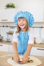 Smiling little girl pushes by a cake tin on a dough on a table