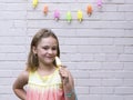 Smiling little girl in rainbow coloured dress holding a popsicle,