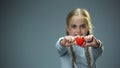 Smiling little girl showing heart figure into camera, love and kindness concept