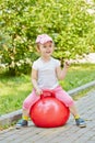 Smiling little girl sits on red ball for jumping Royalty Free Stock Photo