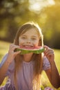 Smiling little girl sitting in nature and eating watermelon. Looking at camera Royalty Free Stock Photo