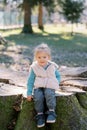 Smiling little girl sitting on stump in spring sunny park Royalty Free Stock Photo