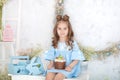 Smiling little girl sitting at white table in kitchen with Easter panettone. Easter interior. Spring home decor. Happy family gett