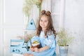 Smiling little girl sitting at white table in kitchen with Easter panettone. Easter interior. Spring home decoration. Happy family