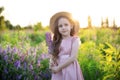 Smiling little girl in straw hat holds lupine flower in her hands at sunset. Child Girl in field of lupines. Childhood concept. Co Royalty Free Stock Photo