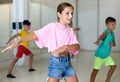 Smiling little girl training vigorous dance with group of tweens