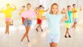 Smiling little girl training vigorous dance with group of tweens