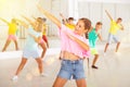 Smiling little girl training vigorous dance with group of tweens