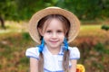 Smiling little girl with two pigtails on her head and in a straw hat in garden. Childhood concept. Closeup portrait of happy child Royalty Free Stock Photo