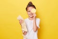 Smiling little girl with wet hair wearing casual white T-shirt standing isolated over yellow background holding eashcloth covering Royalty Free Stock Photo