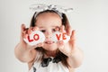 Smiling little girl in white clothes hold white smooth stones with syllables lo and ve painted red on white background. Royalty Free Stock Photo