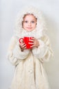 Smiling little girl in winter clothes with a red cup of hot drink. Royalty Free Stock Photo