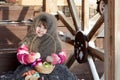 A smiling little girl in a woolen knitted scarf with Christmas tree toys in a basket on the wooden porch of a village house. Selec Royalty Free Stock Photo