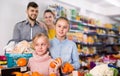 Smiling little girls choosing fresh fruits while shopping with parents Royalty Free Stock Photo