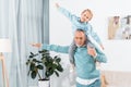 smiling little kid sitting on grandfather shoulders and imitating plane