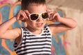 Smiling little kid wearing sunglasses and sailor shirt on graffiti background Royalty Free Stock Photo
