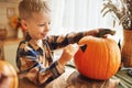 Smiling little kids boy making jack-o-lantern at home, drawing scary face on pumpkin