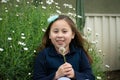 Smiling little latina girl in garden with dandelion