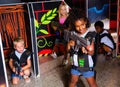 Smiling little mulatto girl aiming laser gun at other players during lasertag game in dark room Royalty Free Stock Photo