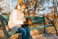 Smiling little owner of a dachshund dog sitting on bench in the autumn park, girl with love hugging dog at the golden hour Royalty Free Stock Photo