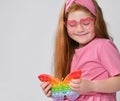 Smiling little red-haired girl child playing with pop it toy studio shot Royalty Free Stock Photo