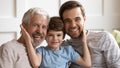 Happy three generations affectionate family looking at camera. Royalty Free Stock Photo