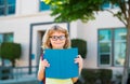 Smiling little student boy wearing school backpack and holding exercise book. Portrait of happy pupil outside the Royalty Free Stock Photo