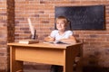 Smiling little student girl sitting at a school desk st classroom. The child is doing homework. Preschool education, back to Royalty Free Stock Photo