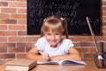 Smiling little student girl sitting at a school desk and studying math. The child is doing homework. Preschool education Royalty Free Stock Photo