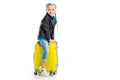 Smiling little tourist sitting on yellow wheel suitcase