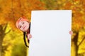Smiling little young girl child in autumn clothes jacket coat and hat holding a blank billboard banner white board. Royalty Free Stock Photo
