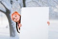 Smiling little young girl child in winter clothes jacket coat and hat holding a blank billboard banner white board. Royalty Free Stock Photo