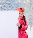 Smiling little young girl child in winter clothes jacket coat and hat holding a blank billboard banner white board. Royalty Free Stock Photo