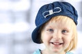 Smiling llittle girl with a cap on her head on a blue background