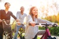 Smiling long-haired little girl with father and mother during outdoor bicycle riding. They enjoy togetherness, happy parenthood Royalty Free Stock Photo