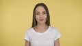 Smiling long-haired woman middle age on yellow background in studio. Middleweight woman in basic white t-shirt