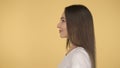 Smiling long-haired woman middle age on yellow background in studio. Middleweight woman in basic white t-shirt