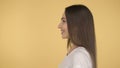 Smiling long-haired woman middle age on yellow background in studio. Middleweight woman in basic white t-shirt