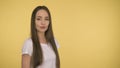 Smiling long-haired woman middle age on yellow background in studio. Middleweight woman in basic white t-shirt