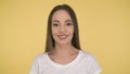 Smiling long-haired woman middle age on yellow background in studio. Middleweight woman in basic white t-shirt