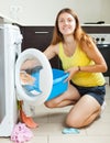 Smiling long-haired woman using washing machine