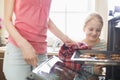 Smiling looking at mother removing cookie tray from oven at home