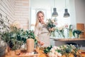 Smiling lovely young woman florist arranging plants in flower shop Royalty Free Stock Photo