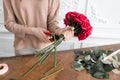 Young woman florist arranging plants in flower shop. People, business, sale and floristry concept. Bouquet of red roses