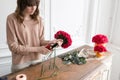 Young woman florist arranging plants in flower shop. People, business, sale and floristry concept. Bouquet of red roses Royalty Free Stock Photo