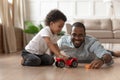 Smiling black dad playing toy cars with little son Royalty Free Stock Photo